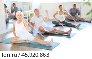 Elderly woman performs stretches elastic band with hand and foot while sitting on mat. Стоковое видео, видеограф Яков Филимонов / Фотобанк Лори