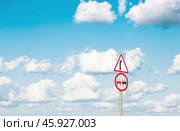 Traffic Laws. Attention. Overtaking is prohibited. A road sign on a metal pole against a background of blue sky and white clouds. Стоковое фото, фотограф Photojuli / Фотобанк Лори