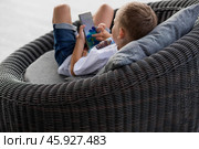 A 5-year-old little boy with a smartphone in his hands on the veranda. The child is playing on the phone. Harm of gadgets for children. Protect your child from the smartphone. Kids and gadgets. Стоковое фото, фотограф Photojuli / Фотобанк Лори