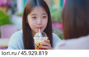 Young woman enjoying a bubble tea drink at an outdoor cafe. Стоковое видео, видеограф Данил Руденко / Фотобанк Лори