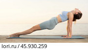 Sporty energetic experienced young woman yoga trainer performing upward plank pose on rug on beach at sunrise. Fitness concept. Стоковое фото, фотограф Яков Филимонов / Фотобанк Лори