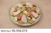Caesar salad with chicken, cherry tomatoes, croutons, parmesan cheese, quail eggs and romaine lettuce. A woman adds cheese to a plate. Traditional American dish. Close-up, selective focus. Стоковое видео, видеограф Наталья Любина / Фотобанк Лори