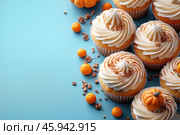 Delicious cupcakes with a fluffy cream topping, topped with cinnamon and fall-themed decorative elements. Some cupcakes feature miniature pumpkins made of mastic or chocolate in the center, adding an accent to the fall season and Halloween. Small round bright orange candies and crunchy crumbs lie next to the cupcakes, adding texture to the composition. The blue background highlights the warm tones of the pastries, creating a pleasant contrast. The overall style of the image is light and festive, perfect for fall themes and dessert photo shoots. Стоковое AI-изображение, AI-художник Анна Кривицкая / Фотобанк Лори