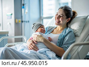 A woman in a hospital bed in the maternity ward. Mom has a newborn baby in her arms. Pregnancy and childbirth. Стоковое AI-изображение, AI-художник Photojuli / Фотобанк Лори