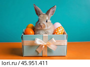 A holiday banner. A cute Easter bunny is peeking out of a gift box, and colorful eggs are scattered around. The concept of happy Easter. Стоковое AI-изображение, AI-художник Photojuli / Фотобанк Лори