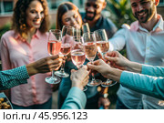 Glasses of pink sparkling wine in the hands of people. People are relaxing on the outdoor veranda. The concept of recreation, corporate event, party or celebration. Стоковое AI-изображение, AI-художник Photojuli / Фотобанк Лори