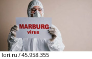 Doctor holding a banner with text Marburg Virus sign. Scientist in protective gear, gloves and medical mask. New epidemic illness. Outbreak of infectious disease spreading, worldwide pandemic. Стоковое AI-видео, аниматор Марина Демидюк / Фотобанк Лори
