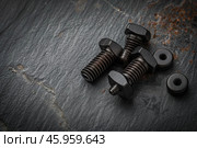 Set of three hex head bolts and washers lying on dark stone surface. Стоковое AI-изображение, AI-художник Иван Рябоконь / Фотобанк Лори