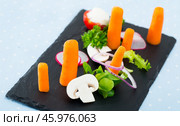 Vegetarian dish, carrots with greens, onion and tomatoe served at black plate. Стоковое фото, фотограф Яков Филимонов / Фотобанк Лори