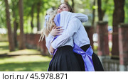 Two joyful female graduates hugging with sashes on their last day of school, commemorating their academic success. Стоковое фото, фотограф Mikhail Davidovich / Фотобанк Лори