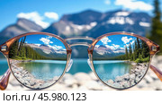 Sunglasses reflecting emerald lake and canadian rockies on sunny summer day. Стоковое AI-изображение, AI-художник Юрий Поздников / Фотобанк Лори