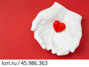 Stylish banner. In his hands, a red heart on a red background is made of plaster. World Health, Love and Insurance Day. World Heart, Health and Organ Donor Day. Стоковое фото, фотограф Photojuli / Фотобанк Лори