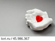 Stylish banner. In his hands, a red heart on a gray background is made of plaster. World Health, Love and Insurance Day. World Heart, Health and Organ Donor Day. Стоковое фото, фотограф Photojuli / Фотобанк Лори