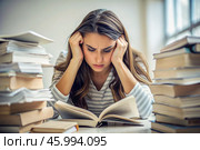 Reads, prepares for exams. use. Admission to the institute. A young girl holds her head among many books, stays at home and studies. Стоковое AI-изображение, AI-художник Photojuli / Фотобанк Лори