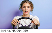 Shocked female learner holding car steering wheel, visualizing unsafe driving situations, emotional stress, driver mistakes, road awareness, driving lessons promotion, safe driving skills. Стоковое AI-изображение, AI-художник Павел Муравьев / Фотобанк Лори
