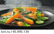 Hot steaming grilled vegetables, carrot, green bean, broccoli, pepper. Serving a white plate on wooden table desk, black wall background. Boiled food healthy meal concept. Ratatouille with smoke steam. Стоковое AI-видео, аниматор Марина Демидюк / Фотобанк Лори
