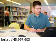 Young male student studying with a laptop in the library. Стоковое фото, фотограф Яков Филимонов / Фотобанк Лори