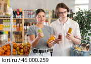 Youth girl and guy friends hold packages bottles and choose consider smoothie in store. Стоковое фото, фотограф Яков Филимонов / Фотобанк Лори