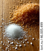 Scattered white and brown granulated sugar on wooden kitchen table. Стоковое AI-изображение, AI-художник Сергей Елизарьев / Фотобанк Лори