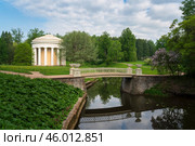 View of the Temple of Friendship on the banks of the Slavyanka River against the background of the Cast-iron bridge in Pavlovsky Park on a sunny summer day, Pavlovsk, St. Petersburg, Russia. Стоковое фото, фотограф Ula Ulachka / Фотобанк Лори