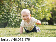 Portrait of a 1-year-old little boy outdoors. A happy child walks in the spring park. Happy childhood and fatherhood. Стоковое фото, фотограф Photojuli / Фотобанк Лори