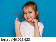 Portrait of happy cheerful little girl lick lollipop candy enjoy sweet snack wear good look clothes isolated over blue color background. Стоковое фото, фотограф Ирина Михайличенко / Фотобанк Лори