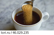 Person adding cane sugar with a spoon to cup of fresh aromatic coffee. Close up of teaspoon putting brown sugar into hot steamed drink mug. Sugar Being Poured into Cup of Coffee Americano, Close-Up. Стоковое AI-видео, аниматор Марина Демидюк / Фотобанк Лори