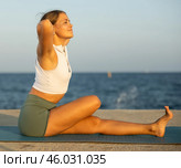 On windy day young slender woman does yoga near sea doing practicing hatha yoga. Стоковое фото, фотограф Яков Филимонов / Фотобанк Лори