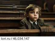 Young boy sitting in church pew listening to sermon. Стоковое AI-изображение, AI-художник Иван Рябоконь / Фотобанк Лори