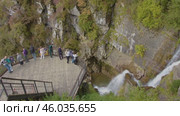 Tourists take pictures of the impressive waterfall in Mendelikha Park, located in the Caucasus mountains. Туристы фотографируют великолепный водопад в парке Менделиха среди гор Кавказа. Редакционное видео, видеограф Валерий Тесаков / Фотобанк Лори