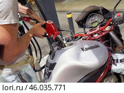 Kawasaki motorcycle being refueled at gas station. Close up of biker full-up Motorcycle tank during travel maintenance. Motorcycle is refueling process concept: Zabbar, Malta - 01.07.2020. Редакционное фото, фотограф Kira_Yan / Фотобанк Лори