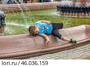 Ребенок играет на краю фонтана с водой (2022 год). Редакционное фото, фотограф Юрий Шурчков / Фотобанк Лори