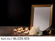 Blank funeral frame, candles and flowers on table against black background. Стоковое фото, фотограф Pixel_shot / Фотобанк Лори