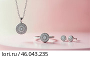 Elegant jewelry set(locket on chain, ring and poussette earrings) in white metal and gemstone on pink background. Copy space. AI generative. Стоковое AI-изображение, AI-художник Роман Дзюбало / Фотобанк Лори