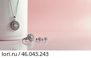 Elegant jewelry set of chain locket, ring and earrings on a shiny white and pink background. The pink surface reflects the jewelry. Copy space. AI generative. Стоковое AI-изображение, AI-художник Роман Дзюбало / Фотобанк Лори