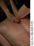 Rehab back massage with elbow, hands of female masseur doing medical backbone massage for patient in dark medical room in shadow. Healthy relax massaging. Wellness, health concept. Copy ad text space. Стоковое фото, фотограф Aleksandr Golubev / Фотобанк Лори