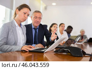 Mature businessman prompts and helps businesswoman during business meeting. Стоковое фото, фотограф Яков Филимонов / Фотобанк Лори