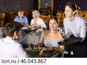 Waitress serves order of wine and wishes visitors young couple pleasant appetite and good time. Стоковое фото, фотограф Яков Филимонов / Фотобанк Лори