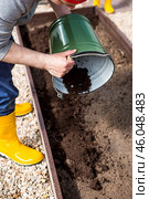 A male farmer pours new soil, soil for a new greenhouse. The concept of spring vegetable planting, greenhouse installation and farming. Стоковое фото, фотограф Photojuli / Фотобанк Лори