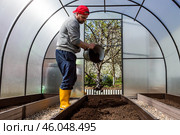 A male farmer pours new soil, soil for a new greenhouse. The concept of spring vegetable planting, greenhouse installation and farming. Стоковое фото, фотограф Photojuli / Фотобанк Лори