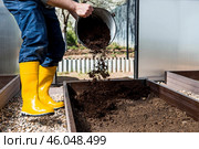 A male farmer pours new soil, soil for a new greenhouse. The concept of spring vegetable planting, greenhouse installation and farming. Стоковое фото, фотограф Photojuli / Фотобанк Лори