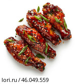 Delicious glazed chicken wings garnished with sesame seeds and green onions. Стоковое AI-изображение, AI-художник Иван Рябоконь / Фотобанк Лори