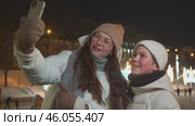 Boy takes photo with his mom in front of big ice rink with lights and decorations. boy and mom wave to people on internet. They smile and look happy. Стоковое видео, видеограф Strunov David / Фотобанк Лори
