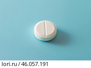 White round pill divisible in two lying on blue background. Стоковое AI-изображение, AI-художник Иван Рябоконь / Фотобанк Лори