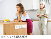 Senior woman scolding her adult daughter cooking breakfast in modern kitchen. Стоковое фото, фотограф Яков Филимонов / Фотобанк Лори
