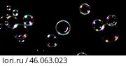 Beautiful iridescent soap bubbles floating against black background showcasing vibrant colors and reflections, ideal for backgrounds overlays creative projects, evoking sense of wonder. Стоковое фото, фотограф Павел Муравьев / Фотобанк Лори