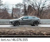 Gray sports car Lamborghini Urus is driving down the street. Side view of fast moving SUV car on the country road. Редакционное фото, фотограф Константин Григорьев / Фотобанк Лори