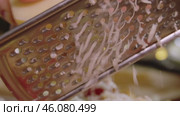 Fresh cheddar cheese is grated on a small cheese grater and then added to an appetizing dish. Slow motion. Стоковое видео, видеограф Strunov David / Фотобанк Лори