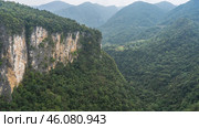 Impenetrable thickets of tropical forest on the slopes of mountains and in the gorge. A sheer cliff in the foreground. A haze in the distance.View from the Zhangjiajie Glass Bridge to the Grand Canyon. Стоковое фото, фотограф Вера Ивановна Кубарева / Фотобанк Лори