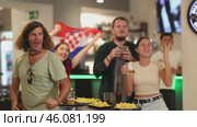 Happy sports supporters with flag of Croatia, rejoicing winning game with beer and snacks in pub. Стоковое видео, видеограф Яков Филимонов / Фотобанк Лори